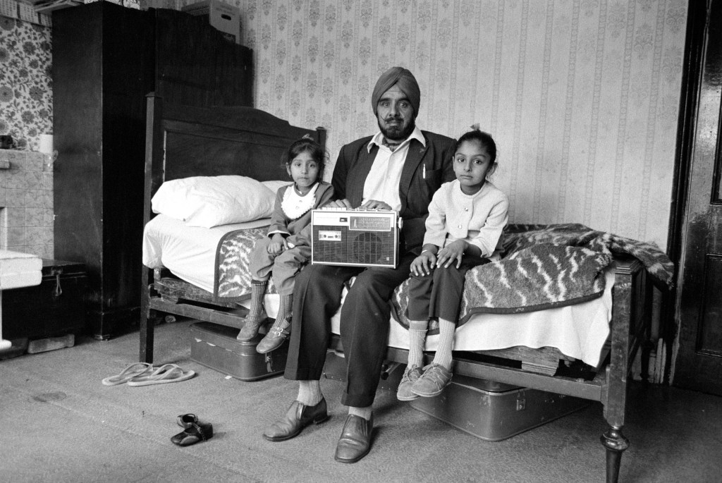 Man with his two daughters and his most prized possession, Southall, 1976. Image Credit: Dennis Morris SINGLE USE ONLY