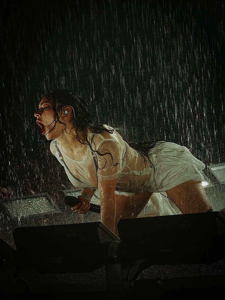 charli xcx performing on stage in the rain