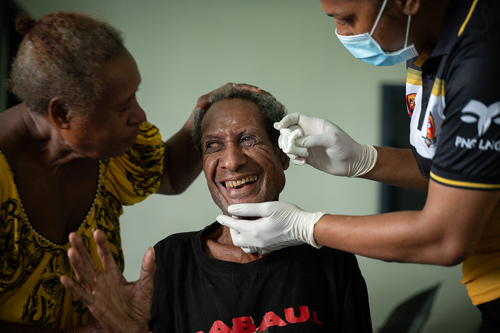 photo of a man laughing while having his eyes tended to by nurse submitted for world sight day