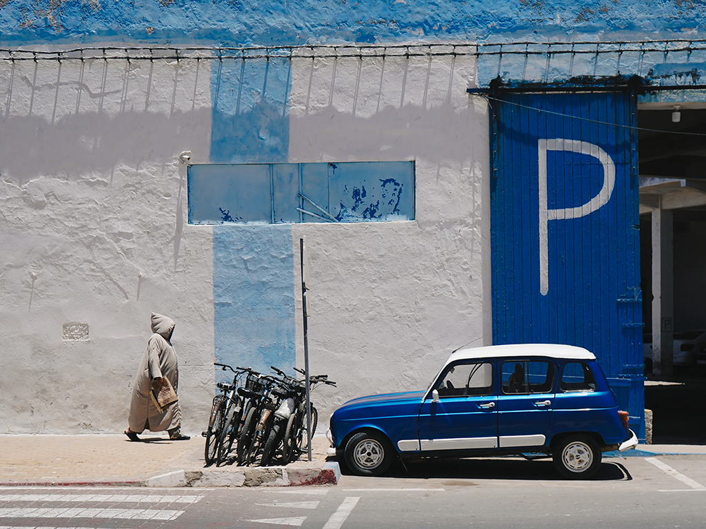 small blue car parked in front of a blue and white building