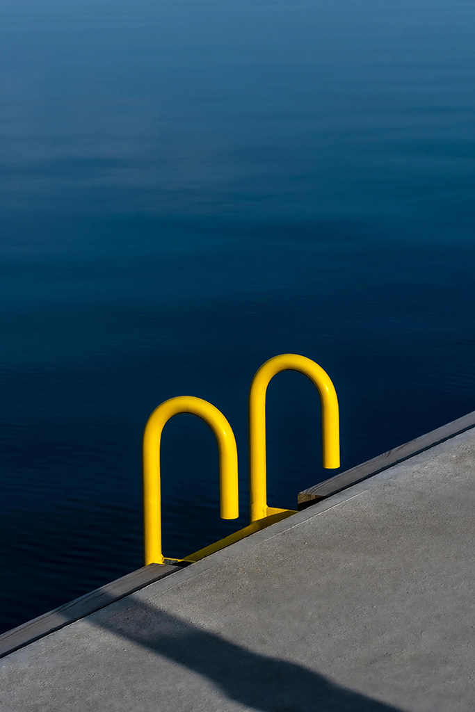 yellow step ladder arms against blue water