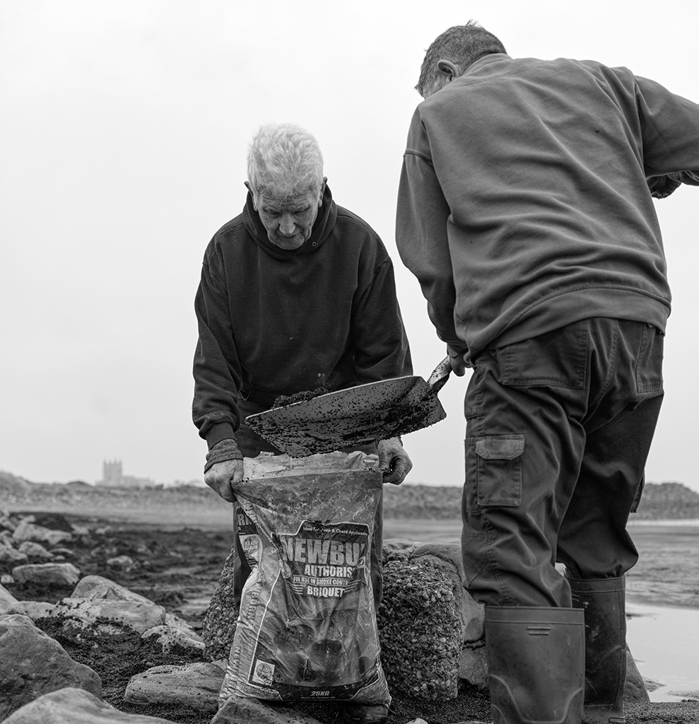 photo of two people shovelling into bag