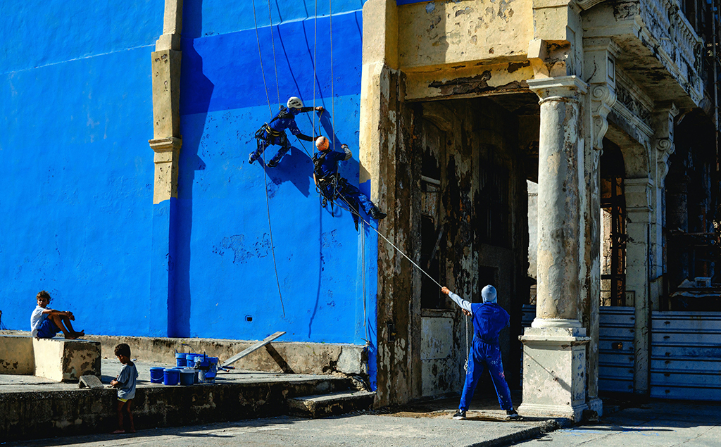 people in harnesses leaning against bold blue wall