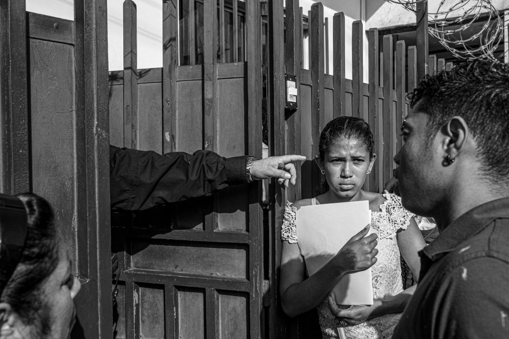 Asylum seekers wait at the gates of the Mexican Commission for Aid to Refugees (COMAR) for an asylum hearing. Tapachula, Mexico 2019. From the series “The Two Walls” © Alejandro Cegarra/LOBA 2025