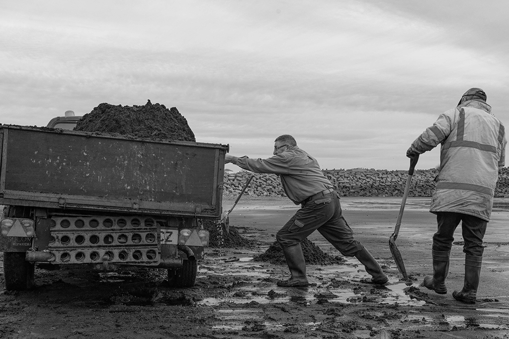 man pushing truck of dirt