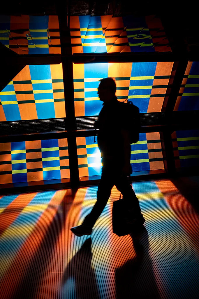 silhouette of man walking past orange and blue wall