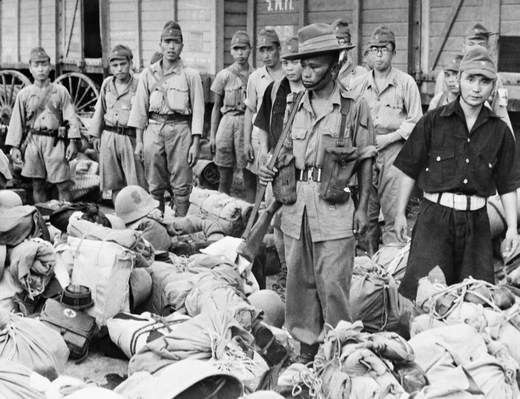 Japanese Troops Leave Bangkok, 1945, One of the Gurkha sentries posted to oversee disarmed Japanese soldiers as they wait to board trains that will carry them to prisoner of war camps outside the city of Bangkok, September 1945. (Photo by No 9 Army Film & Photographic Unit/ Imperial War Museums via Getty Images)