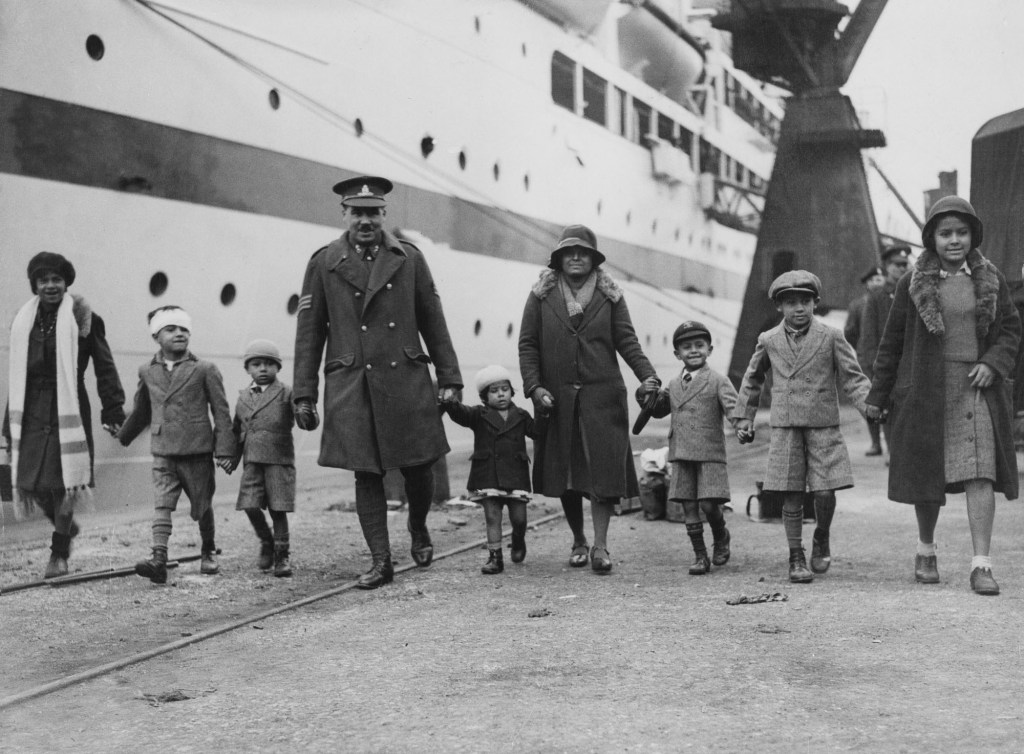 A sergeant of the Royal Artillery pictured with his wife and their seven children on arrival at Southampton on the troopship HMS Dorsetshire from India, March 16th 1935. The family are walking along the quayside holding hands. A boy (second left) wears a bandage around his head. (Photo by Keystone/Hulton Archive/Getty Images)