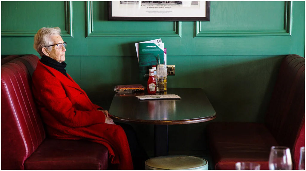 person in red sat against green wall