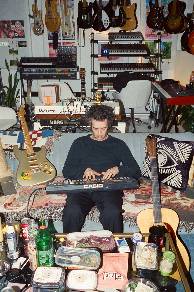 matty healy from 1975 band sat on sofa with keyboard