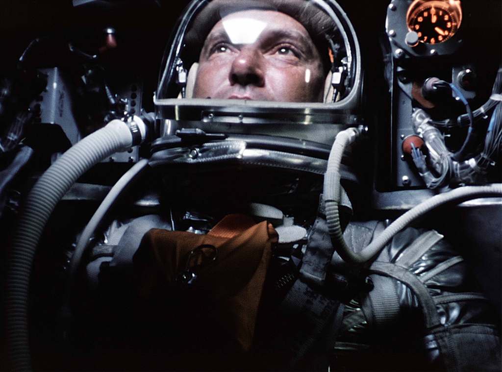 Wally Schirra observes the curvature of Earth (seen reflected in his visor), through the small window of his Mercury spacecraft, 3 October 1962