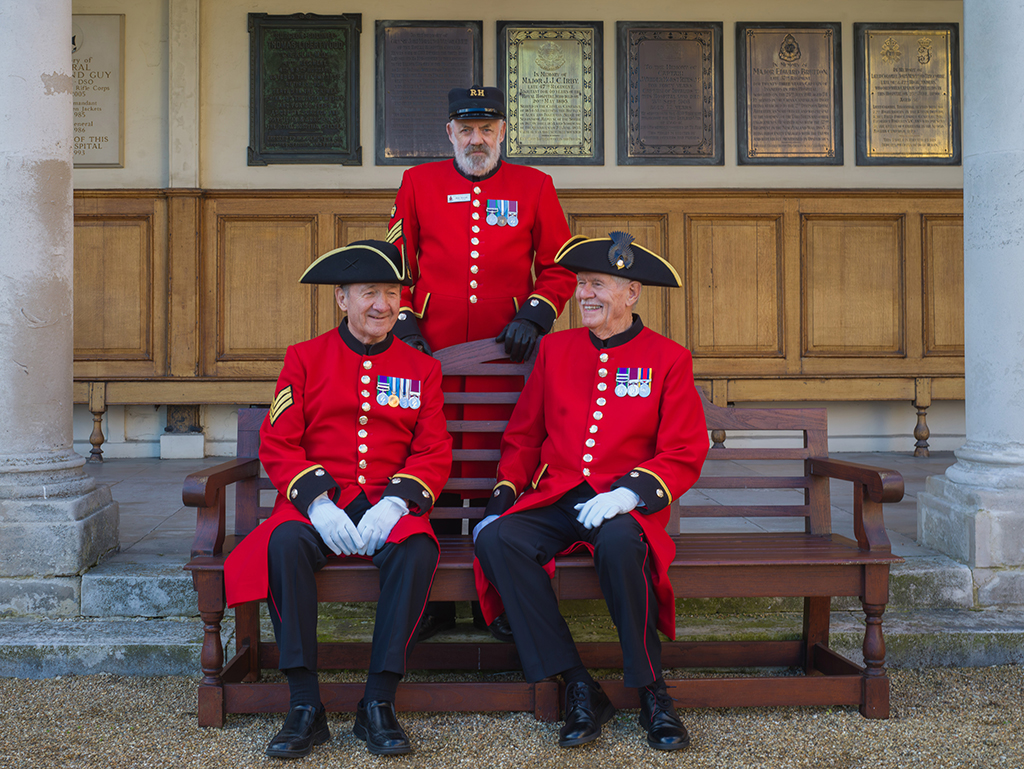 three men in red coat uniform and black hat