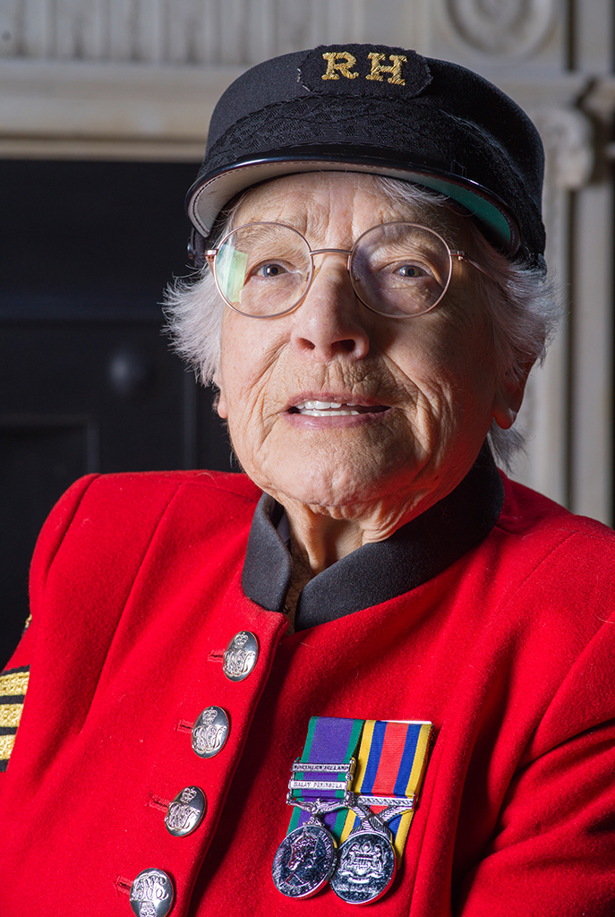 close up portrait of an older woman in red coat uniform and black hat