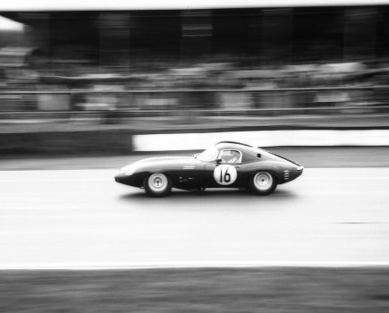 black and white film photo of a car racing at goodwood revival