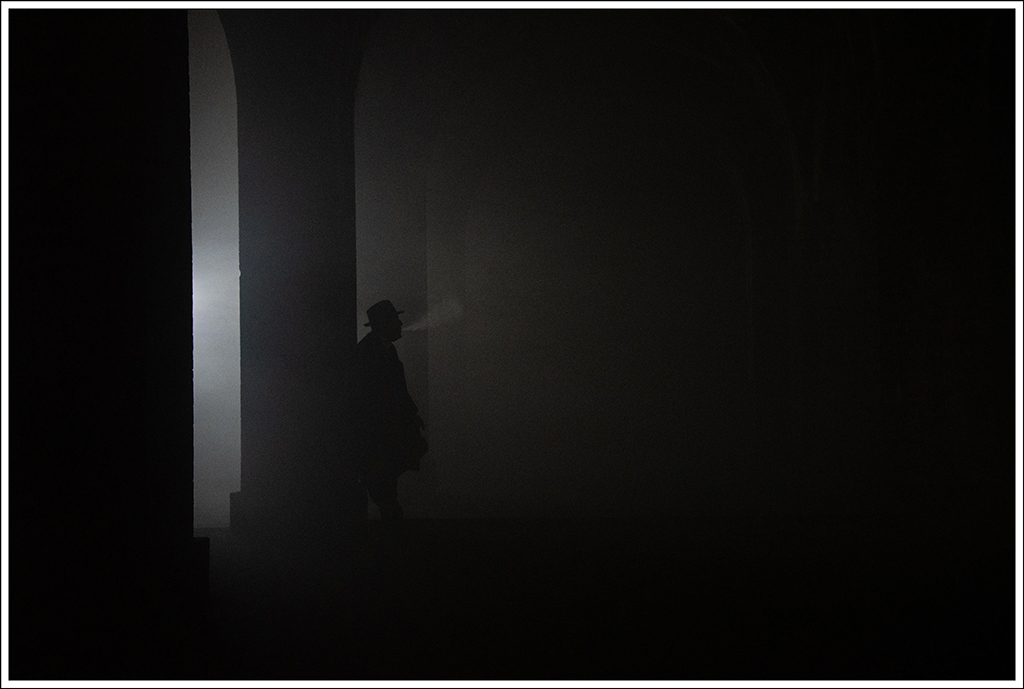 low light street photo in the shadows with discreet silhouette of a man