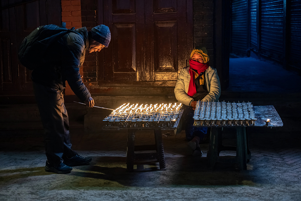 night street scene of person lighting candles