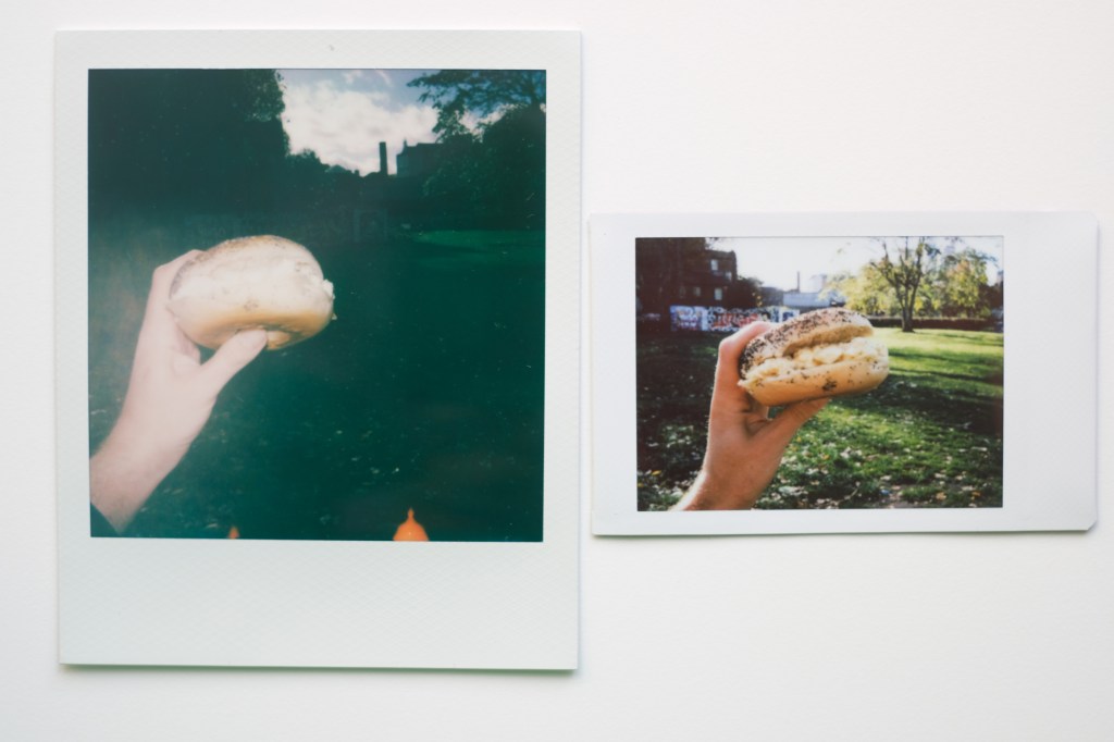 Side by side photographs of an egg bagel from a Polaroid and Instax, the Instax image is much clearer and more pleasant, the Polaroid image having been drowned by flash.