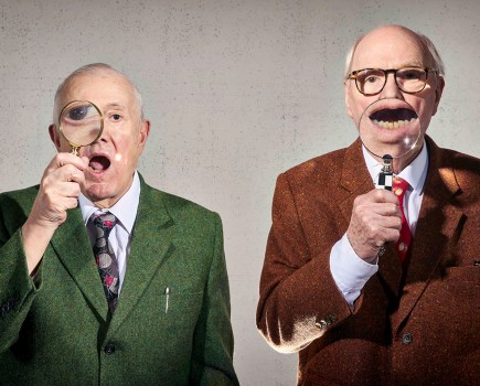 two bald men with magnifying glasses infront of their face