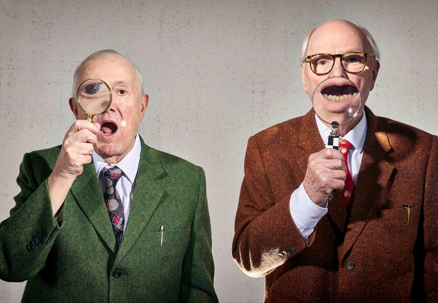 two bald men with magnifying glasses infront of their face