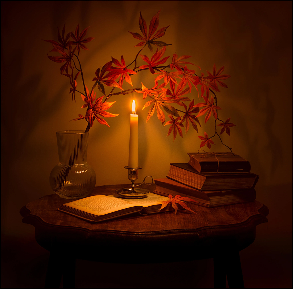 low light still life scene of a candle and maple leaves
