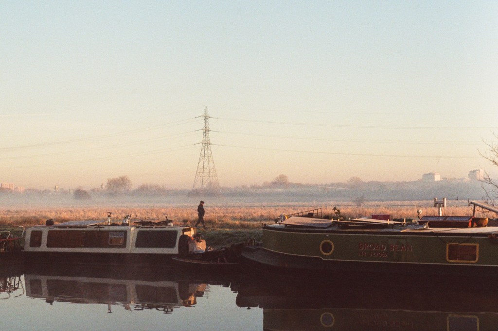 Photo of man walking alongside river in early morning sun on Kodak Ultramax 400 film with Pentax K1000