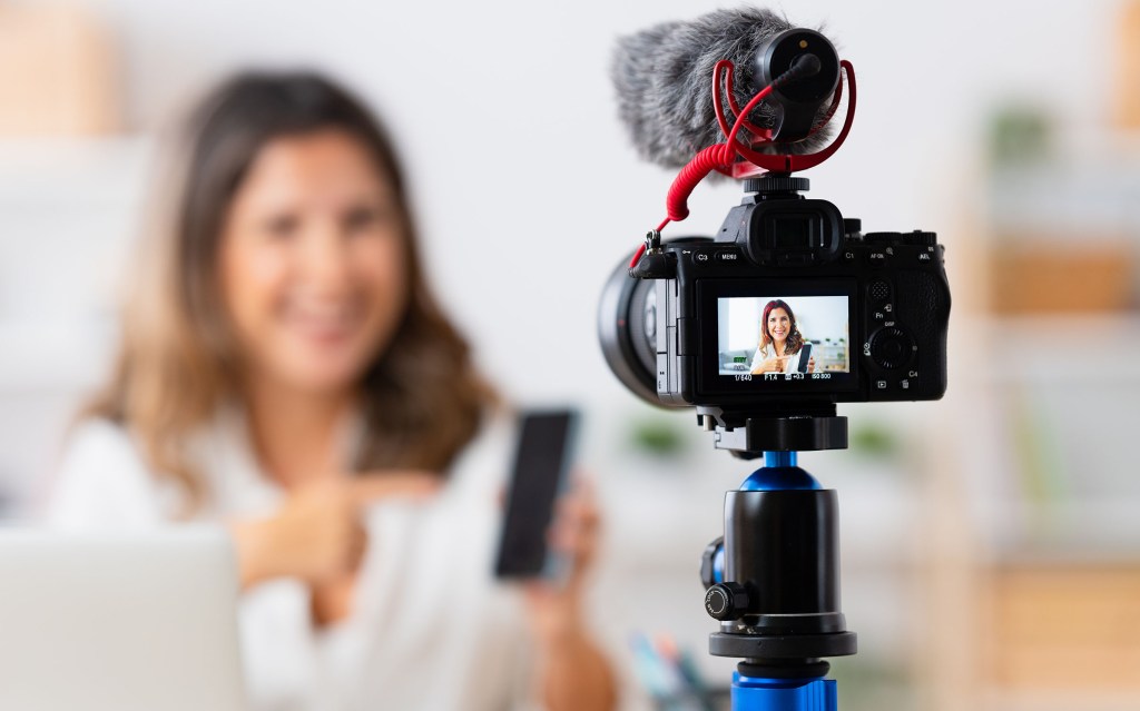Focus on the camera and microphone used by a woman recording a video tutorial from home