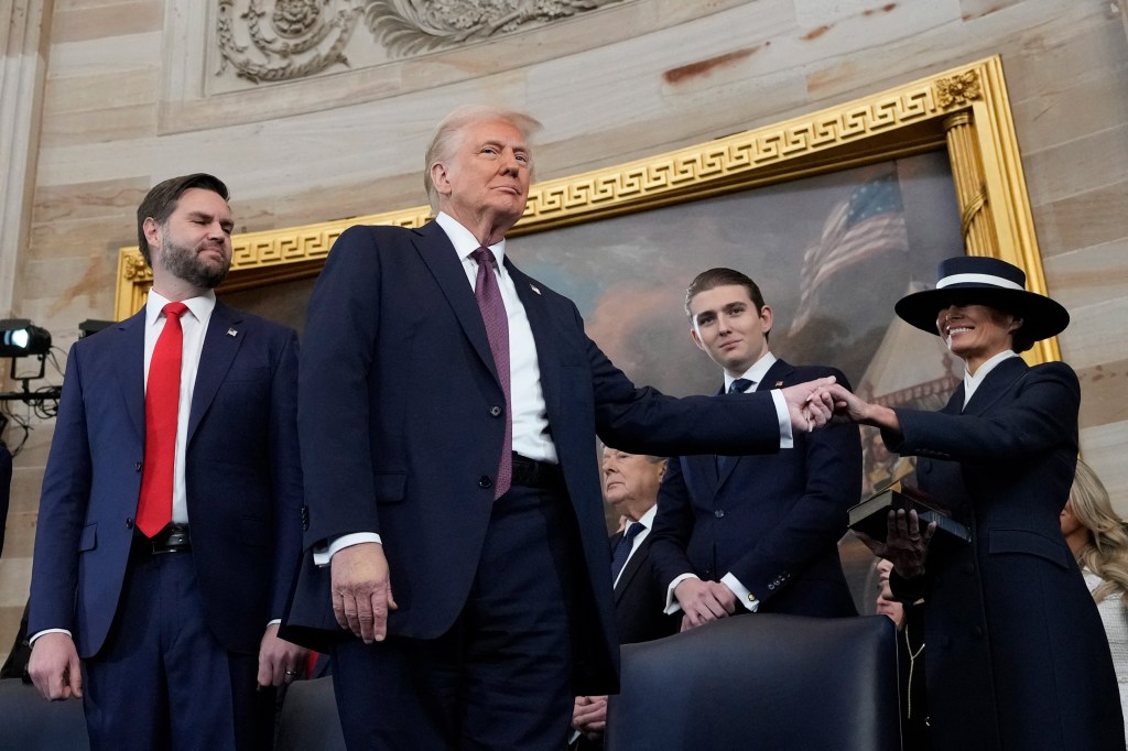 President Donald Trump, center, holds the hand of his wife Melania Trump, right, as their son Barron Trump, center, and Vice President JD Vance, look on after taking the oath of office during the 60th Presidential Inauguration in the Rotunda of the U.S. Capitol in Washington, Monday, Jan. 20, 2025. (Photo by Morry Gash / AFP) (Photo by MORRY GASH/AFP via Getty Images)
