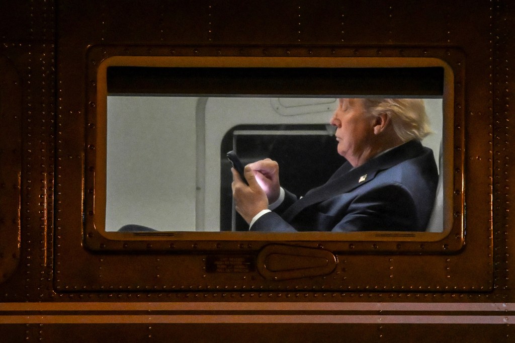 LEESBURG, VIRGINIA - APRIL 24: US President Donald Trump uses a cellphone aboard Marine One before it departs Leesburg Executive Airport in Leesburg, Virginia, on April 24, 2025. Trump is returning to the White House after attending a MAGA, Inc. dinner at the Trump National Golf Club Washington, DC. (Photo by Alex WROBLEWSKI / AFP) (Photo by ALEX WROBLEWSKI/AFP via Getty Images) 