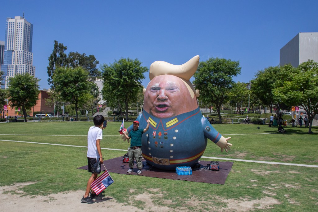 LOS ANGELES, CALIFORNIA - JULY 4: A demonstrator takes a picture of his friend in front of a Trump balloon at the Los Angeles City Hall while they protest against U.S. Immigration and Customs Enforcement (ICE) raids and the presence of the U.S. military in civilian spaces on July 4, 2025 in Los Angeles, California. The demonstration on Independence Day drew activists and community members to the streets, calling for immigration reform and demilitarization. (Photo by Apu Gomes/Getty Images)