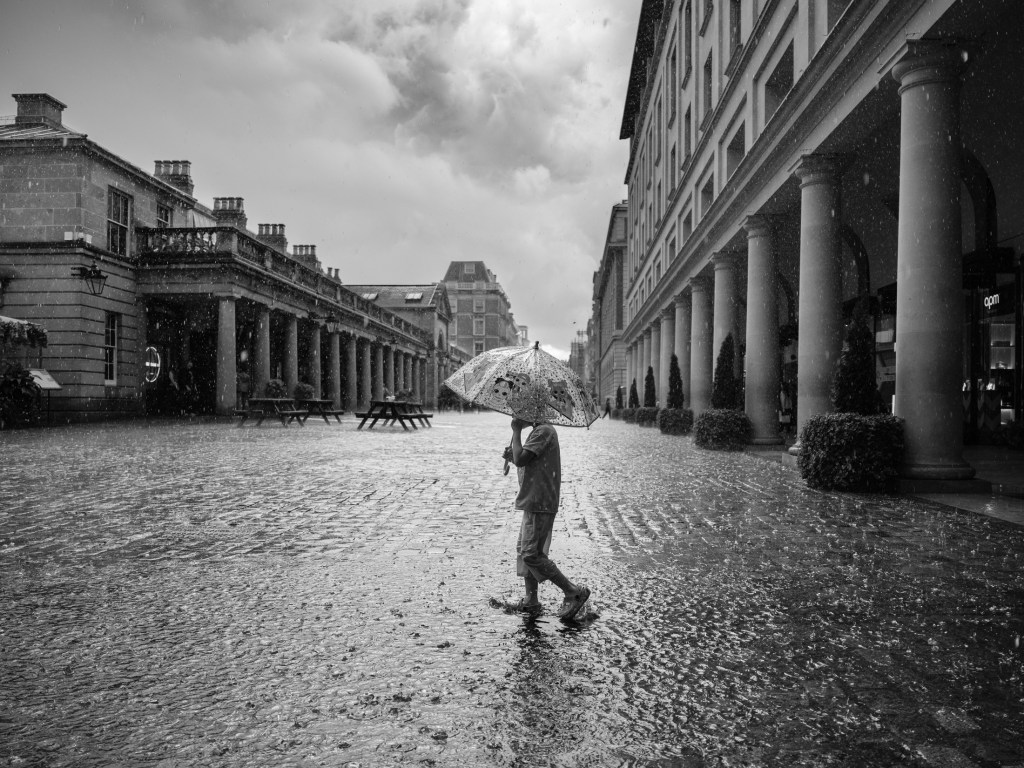 A child plays in a puddle in the summer rain. Covent Garden, London. July 06, 2025. Photo: Edmond Terakopian