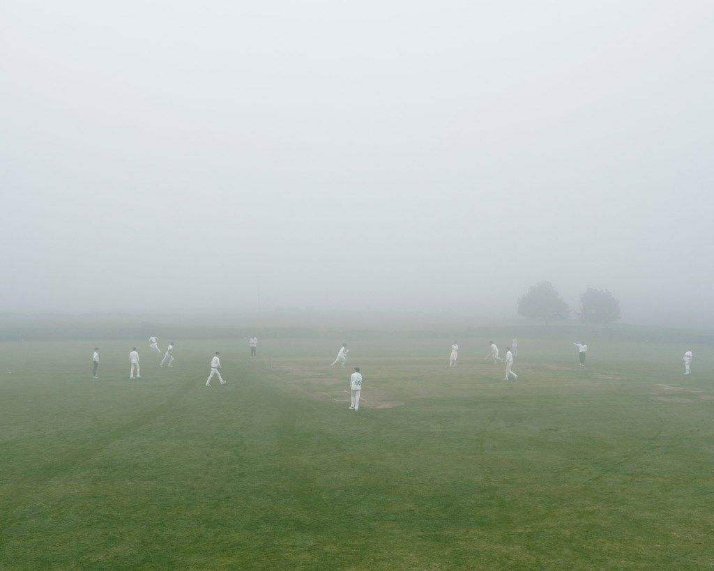 From the series A Portrait of Cricket: A foggy game at the top of the hill at Queensbury Cricket Club, an end of season
match with both sides needing the points so the captains played on regardless. Image Credit: Tom Shaw