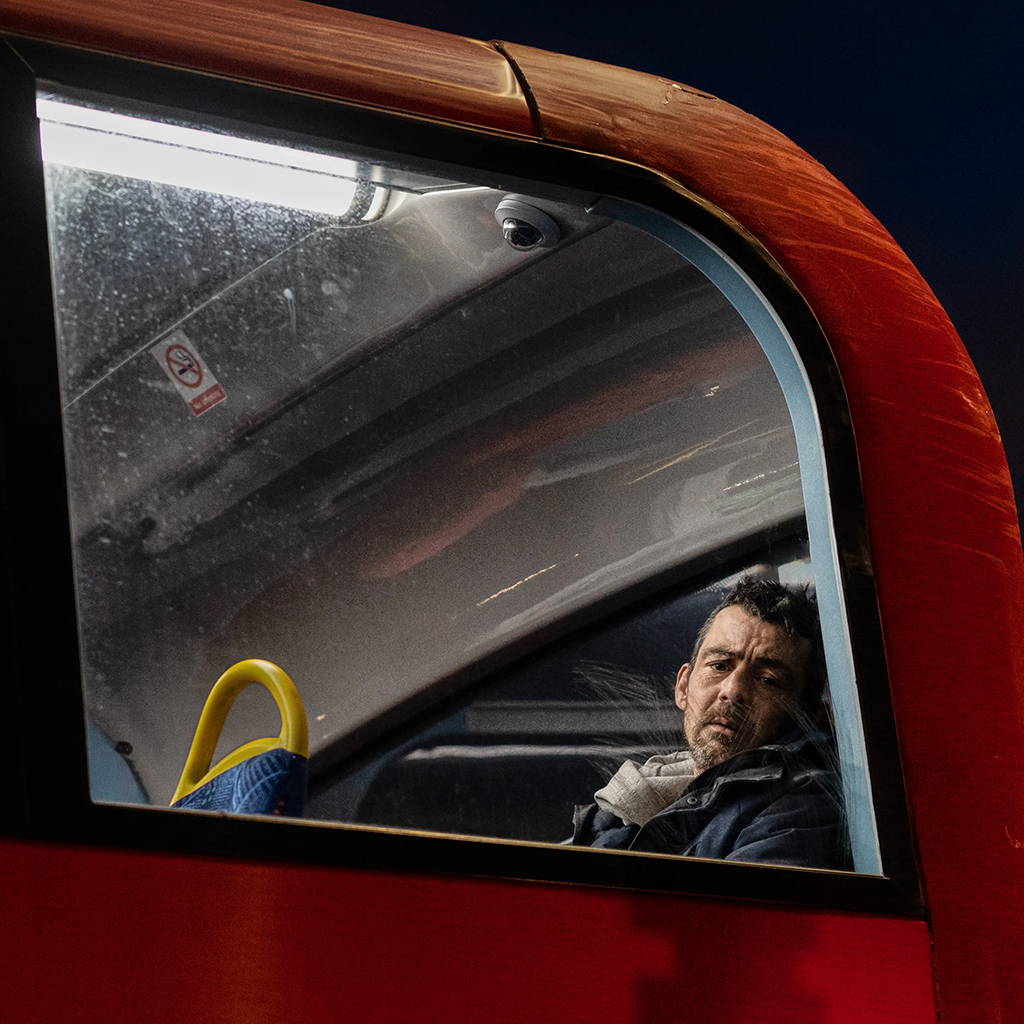 man looking out of red bus window