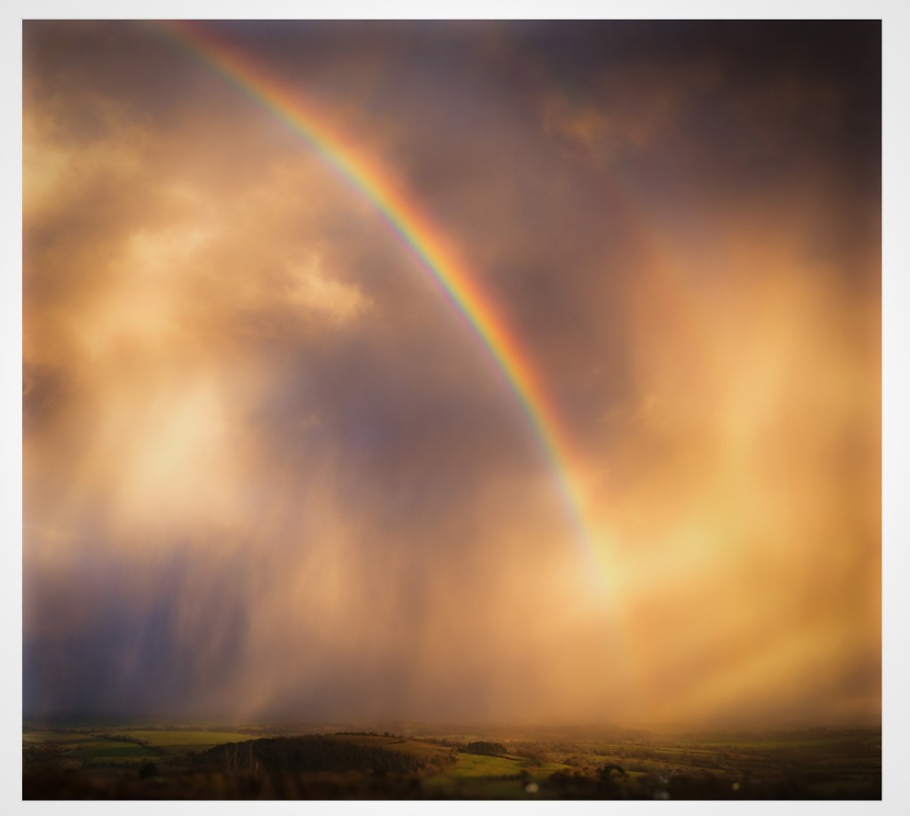rainbow emerging between clouds