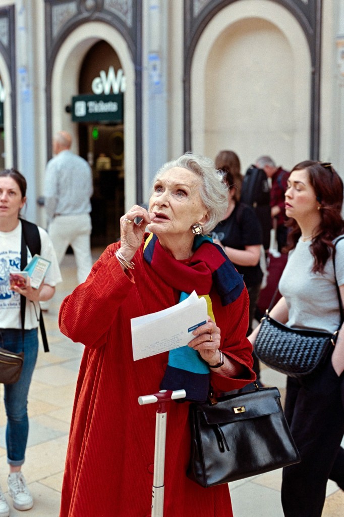 older grey haired lady in a red coat on the street