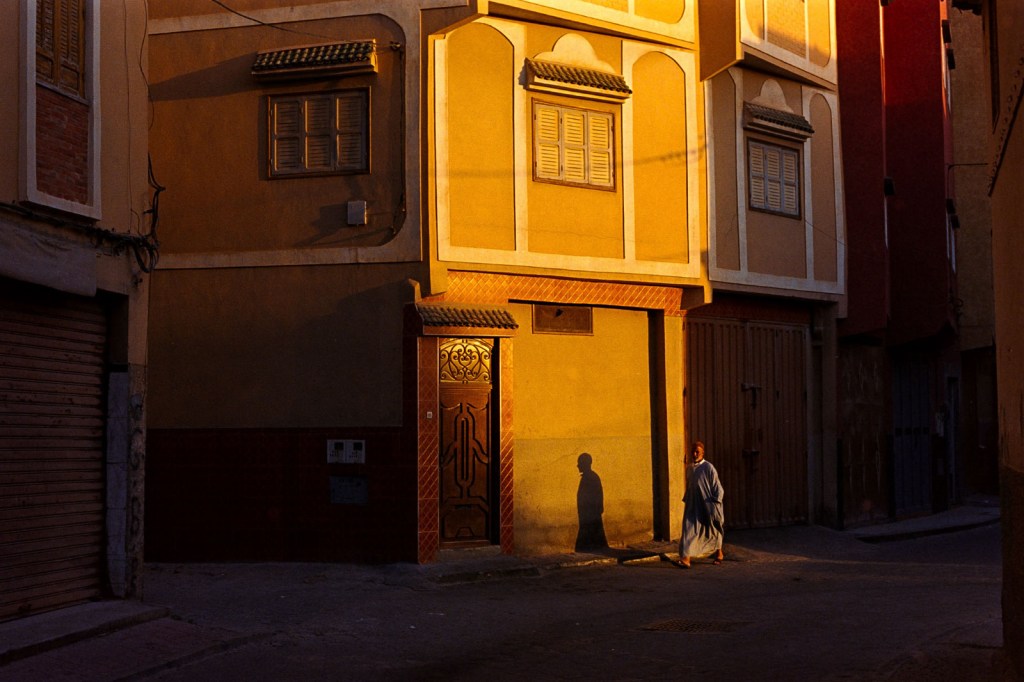shadow shot on a yellow building and person walking between the shadows