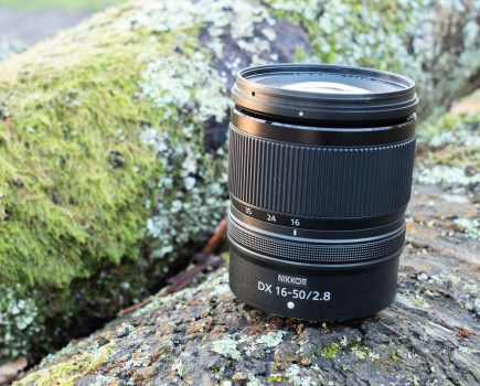 The Nikon Nikkor 16-50mm f/2.8 lens sitting on a wooden log