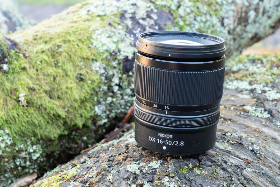 The Nikon Nikkor 16-50mm f/2.8 lens sitting on a wooden log