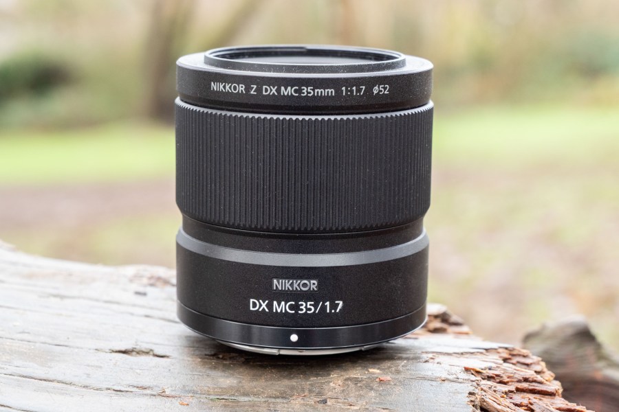The Nikon Nikkor DX MC 35mm f/1.7 lens sitting on a log
