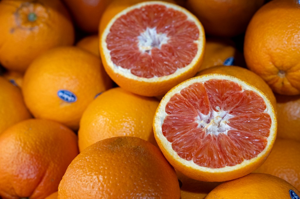 A box full of oranges, including one which has been cut in half