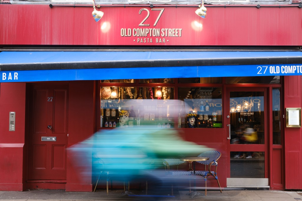 Viltrox TCL-X100VI on Fujifilm X100VI sample image - red shopfront and blurred cyclist.