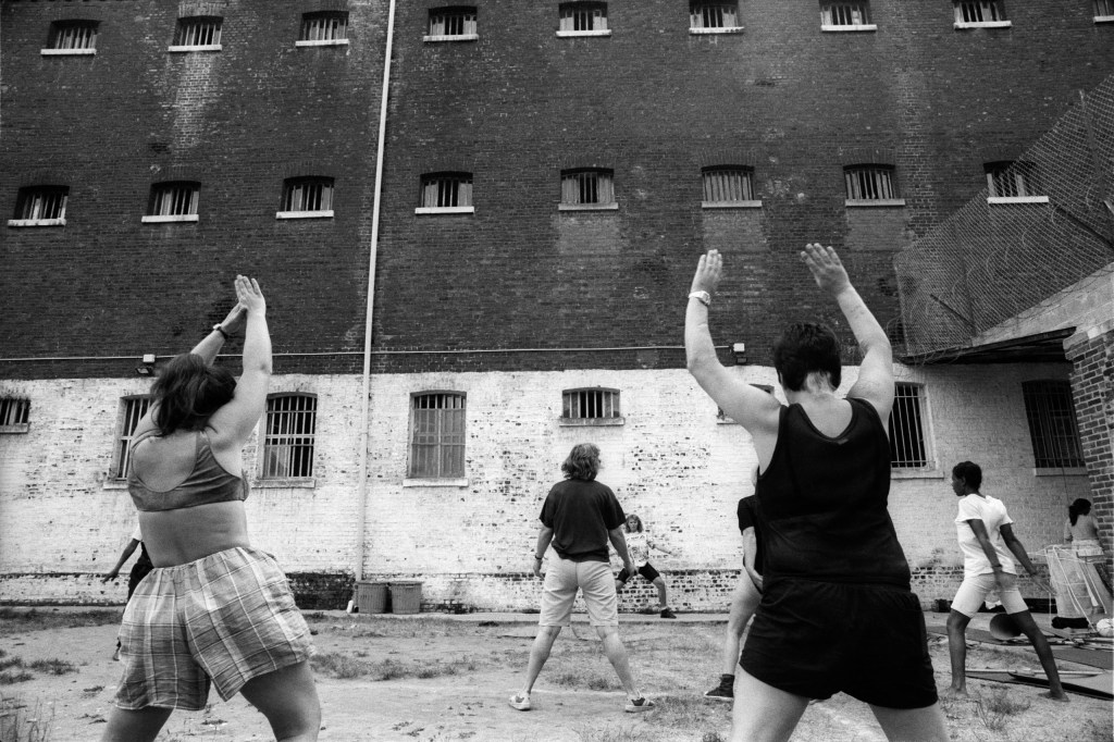 Black and white photograph of prisoners stretching in a prison-yard.