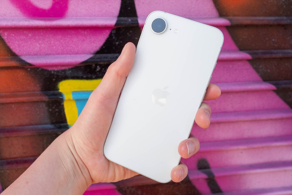An iPhone 17e in front of a vibrant graffitied background