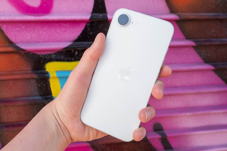 An iPhone 17e in front of a vibrant graffitied background