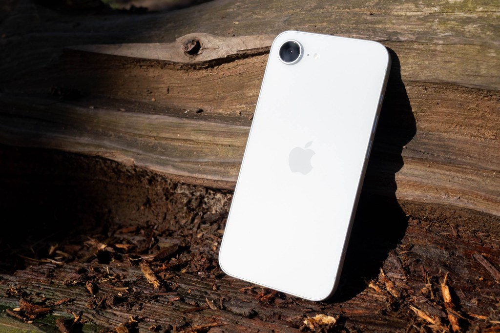 An iPhone 17e resting on a wooden log