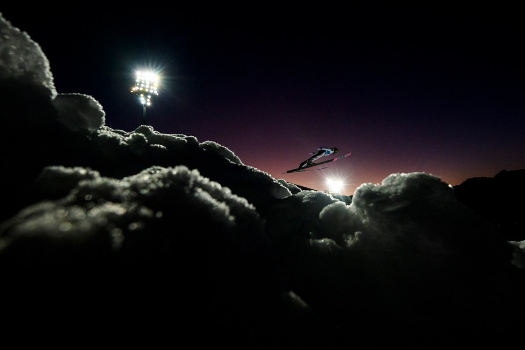 nighttime photo taken at winter olympics of skier mid air