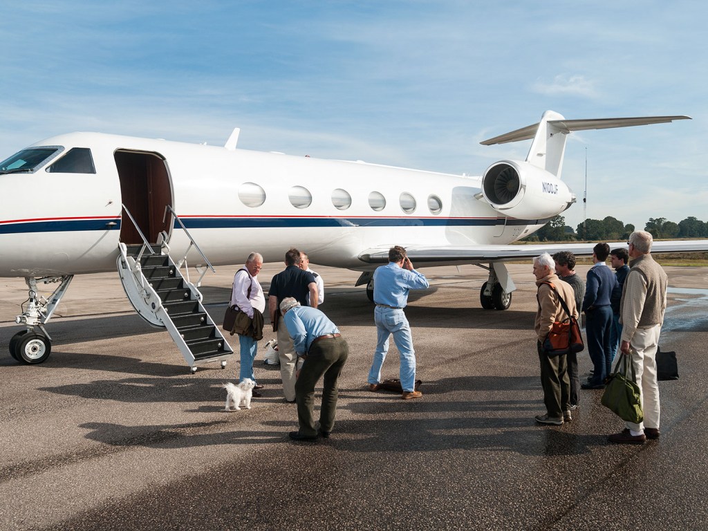 a group of people standing around a private jet