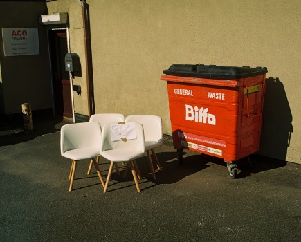 four white chairs next to a red biffa bin