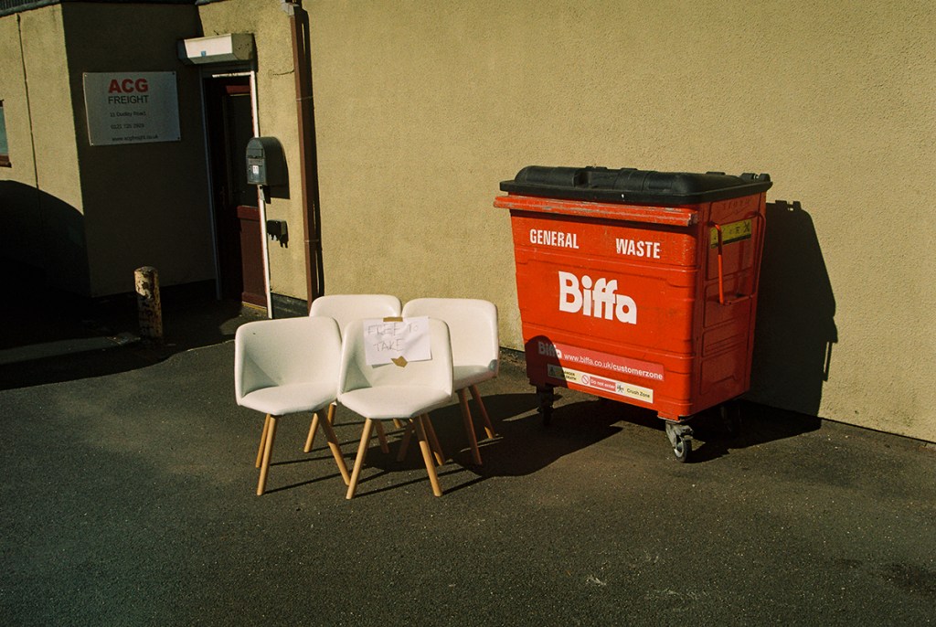 four white chairs next to a red biffa bin