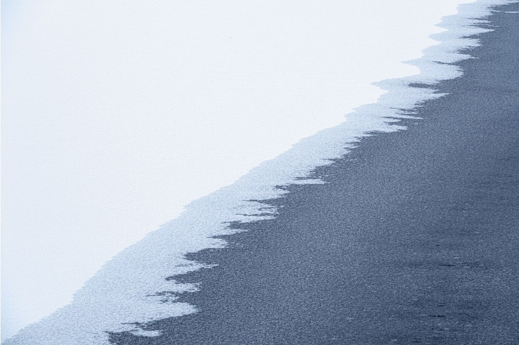 abstract landscape photo of snow meeting black sand