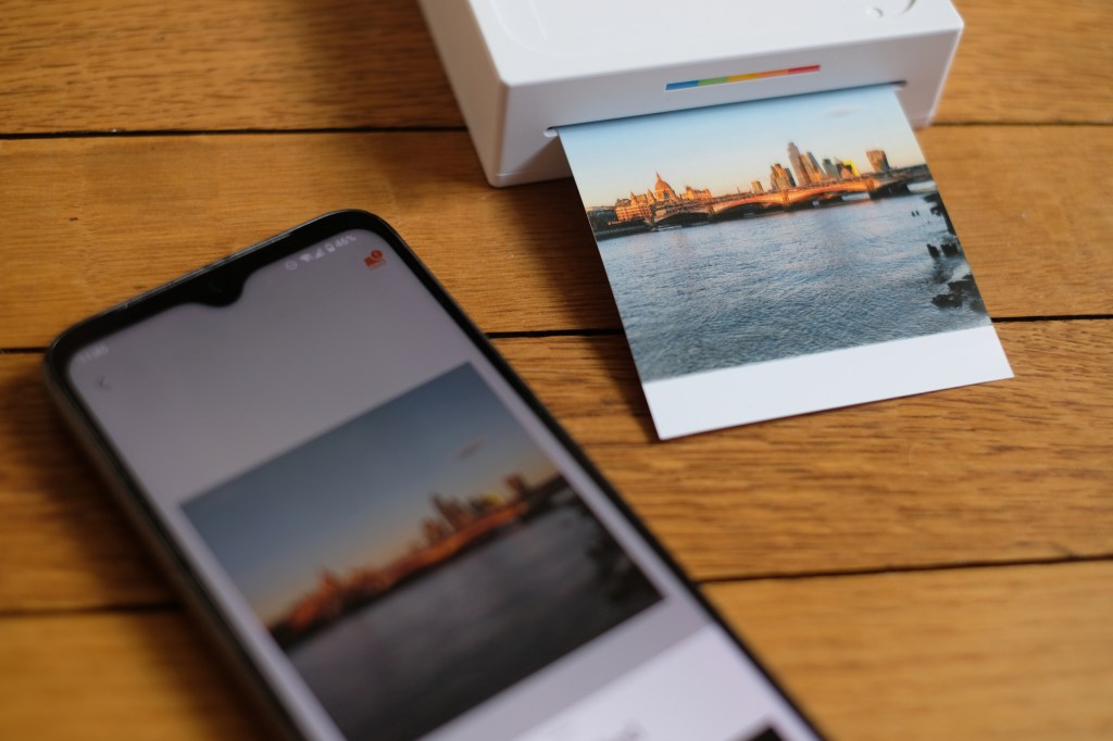 Photograph of Polaroid Hi-Print 3x3 printer mid-print with app visible